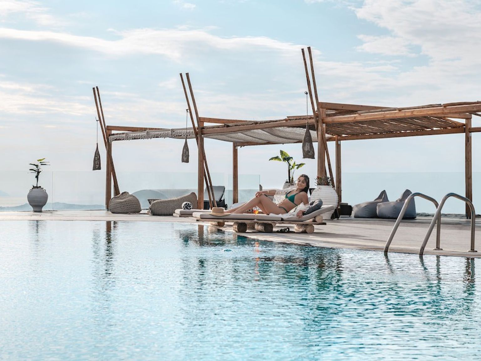 nainen istuu lounge-tuolissa uima-altaan vieressä