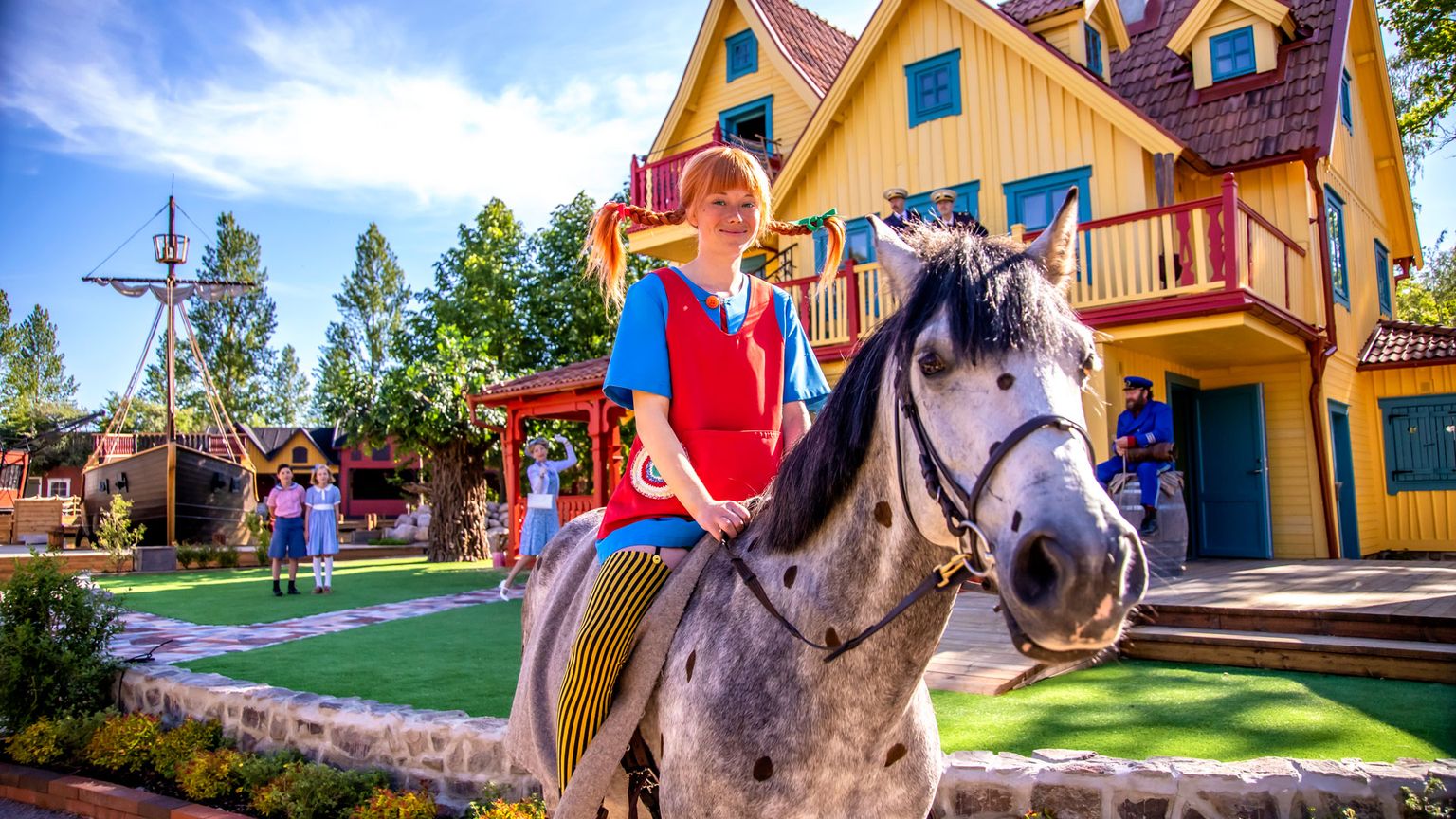 une femme monte à cheval devant une maison jaune