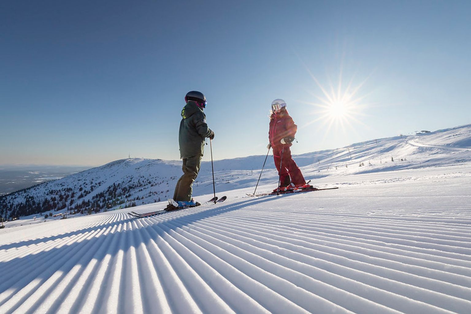 to personer står på ski ned ad en snedækket skråning.