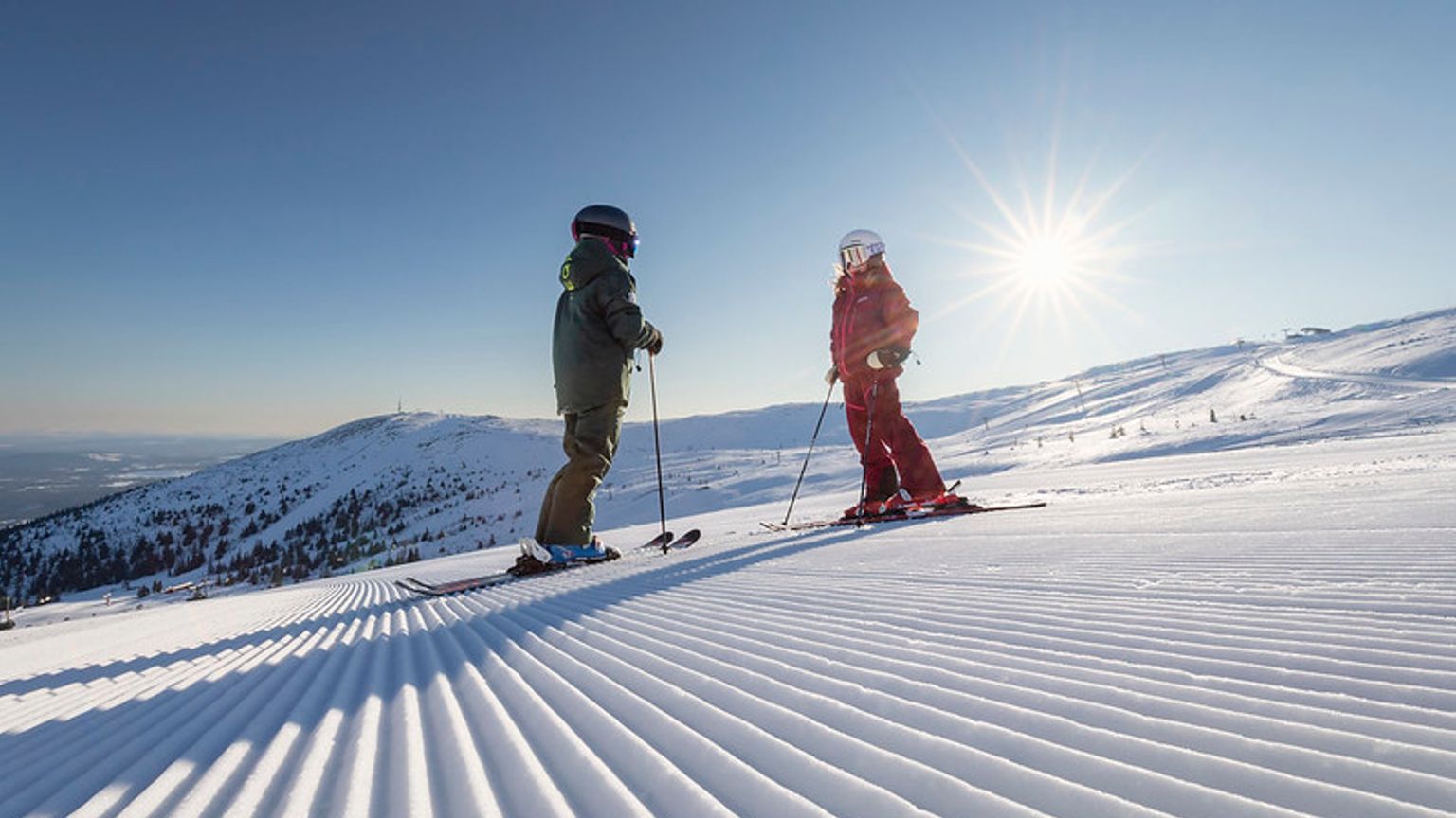to personer står på ski ned ad en snedækket skråning.
