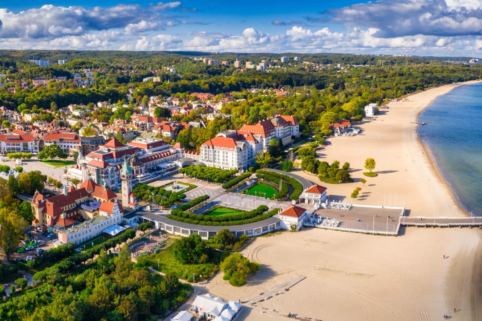 une vue aérienne d'une plage avec une jetée et une ville en arrière-plan.