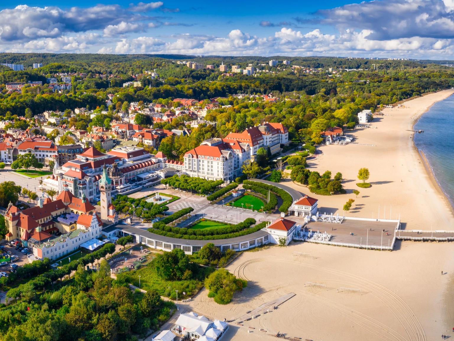 en flygvy av en strand med en pir och en stad i bakgrunden.