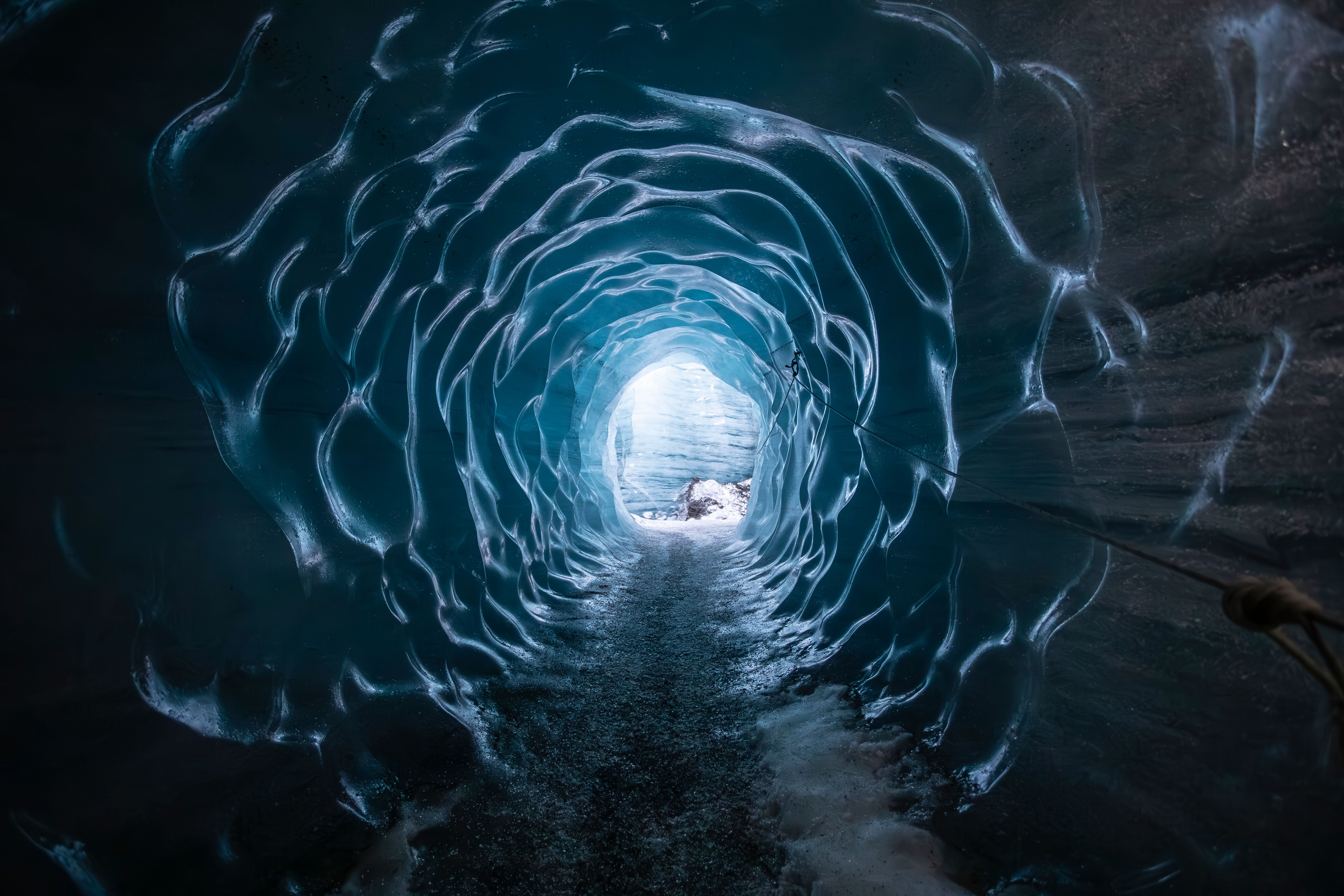 a person is walking through an ice cave with a light at the end