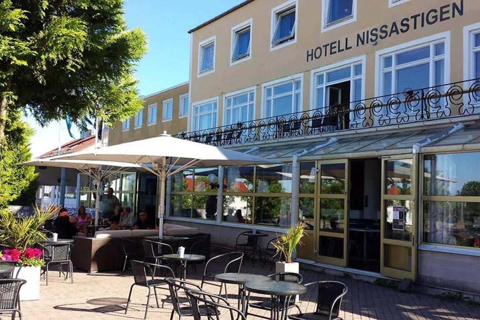 hotel z stolikami, krzesłami i parasolami przed nim