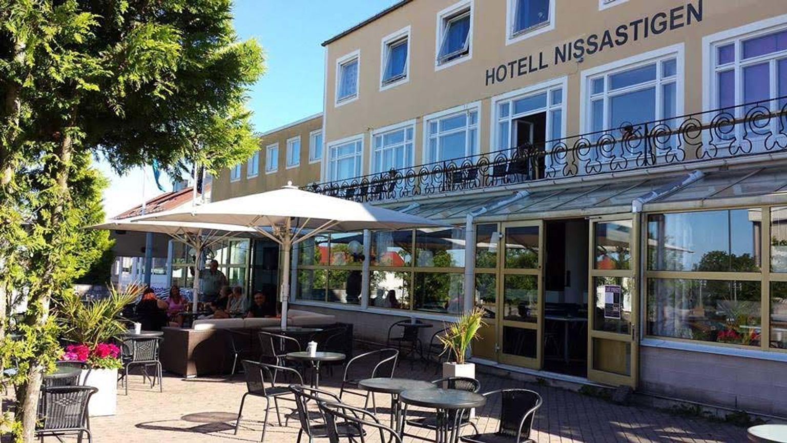 hotel z stolikami, krzesłami i parasolami przed nim