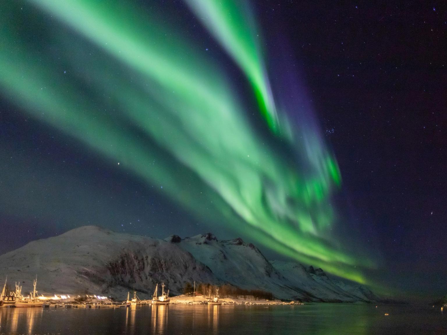 the aurora borealis is shining over a mountain and a body of water