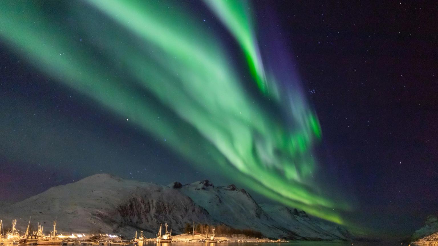 das Nordlicht scheint über einem Berg und einem Gewässer