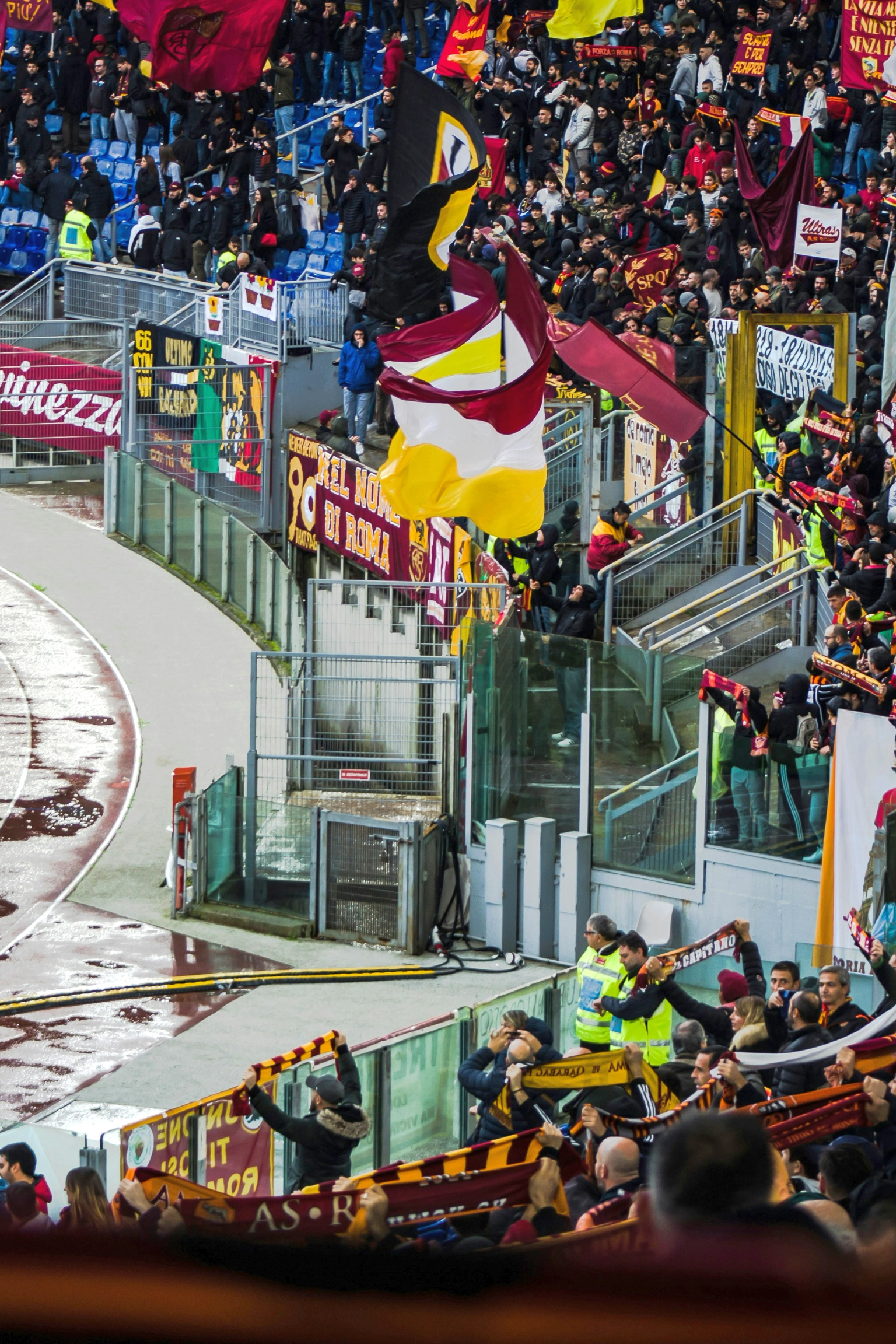 Energiske fans som vifter med flagg og bannere på et stadion med en våt løpebane.