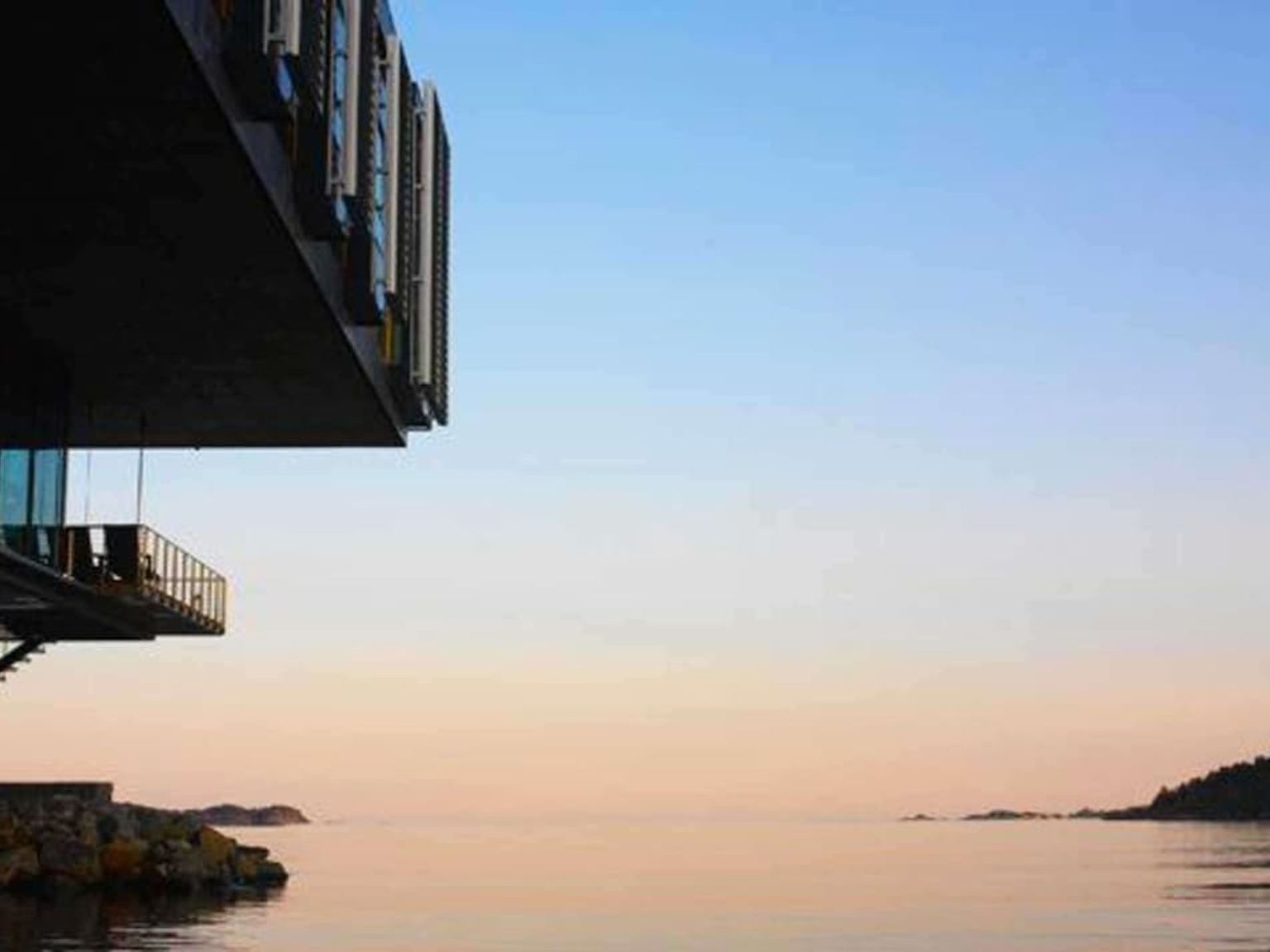 en bygning med en balkong med utsikt over havet ved solnedgang