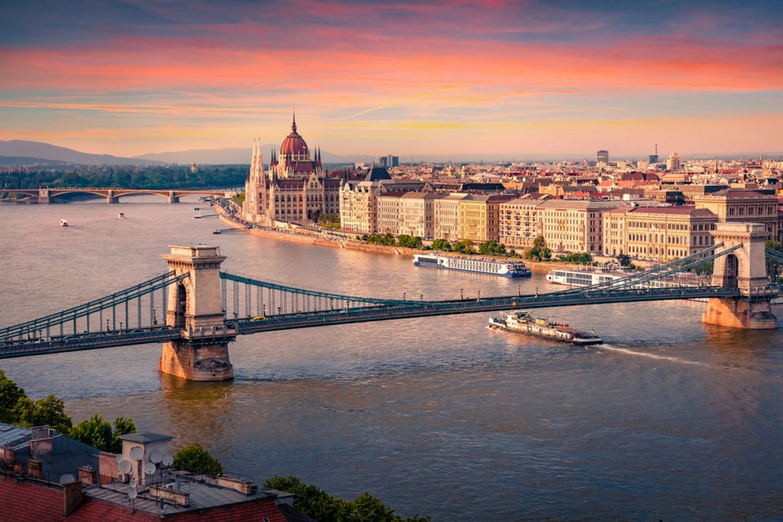 Budapest cityscape at sunset, with the Chain Bridge over the Danube and the Parliament Building.