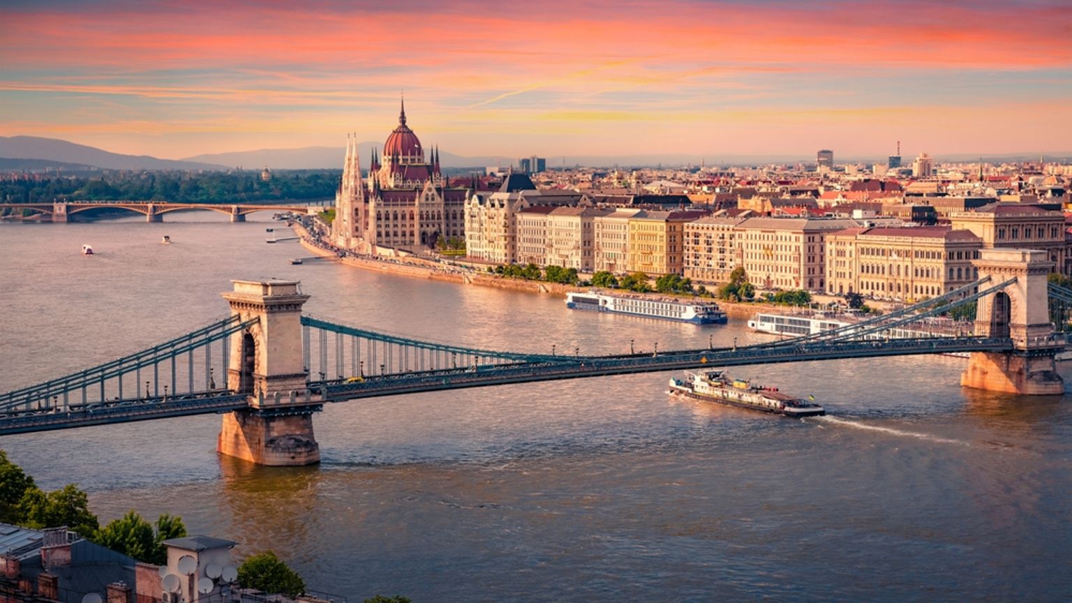 Budapest cityscape at sunset, with the Chain Bridge over the Danube and the Parliament Building.