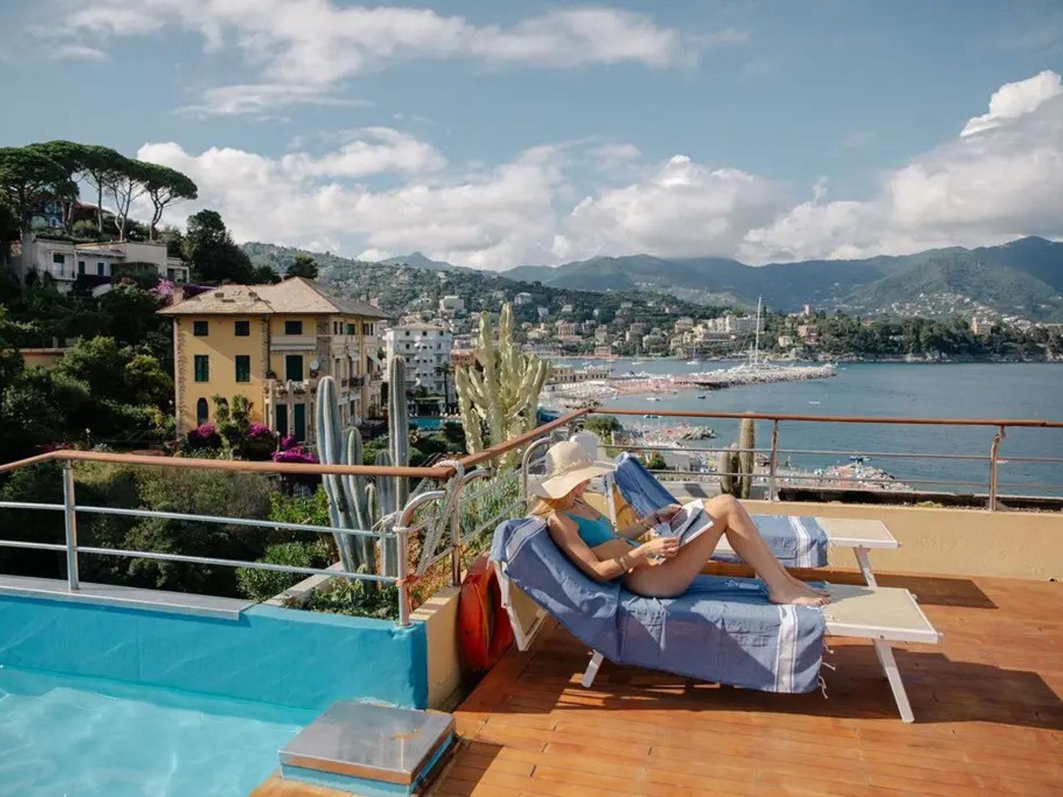 en kvinna sitter på en solstol bredvid en swimmingpool, Hotel Regina Elena