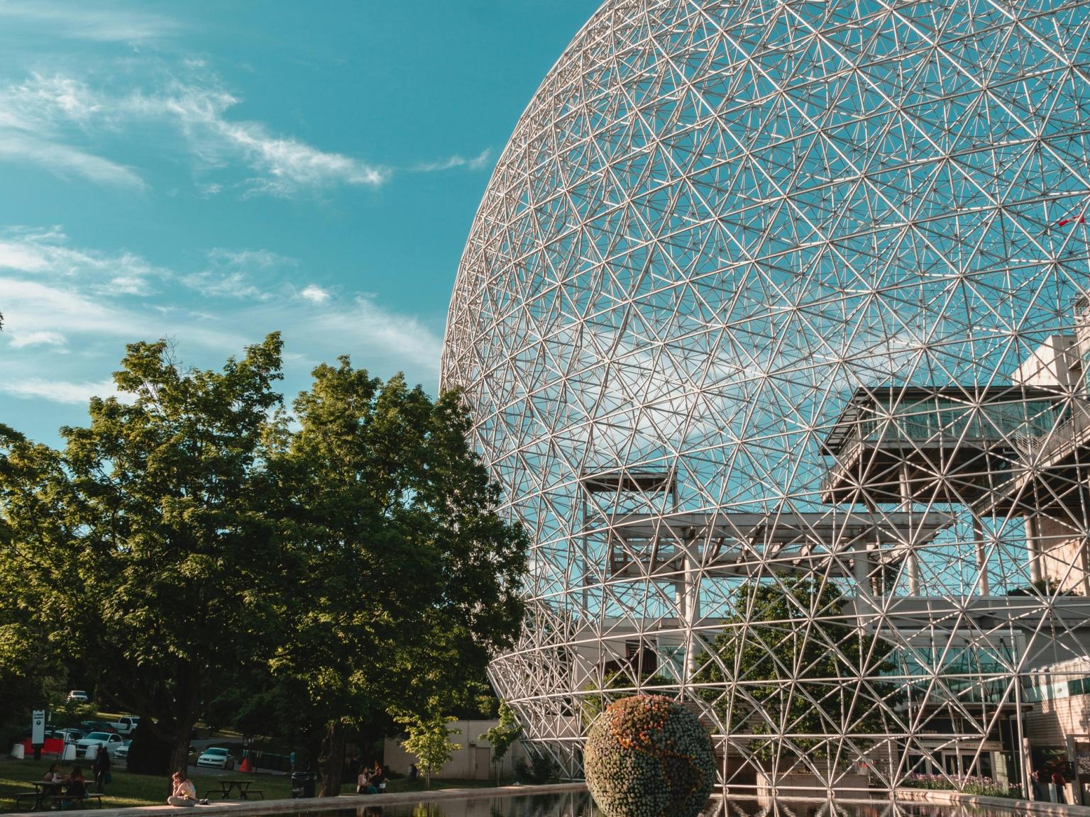 en stor kupol med ett träd framför det speglas i vattnet