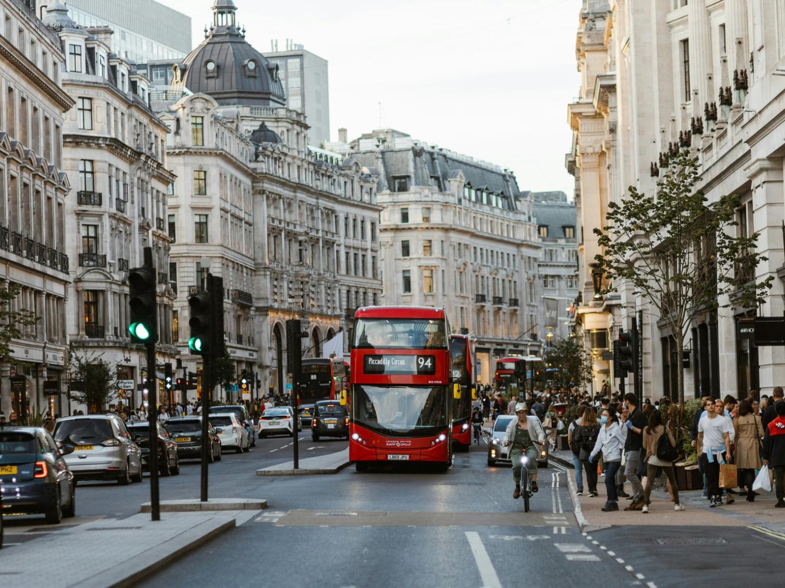 en röd dubbeldäckare kör nerför en livlig stadsgata i London.