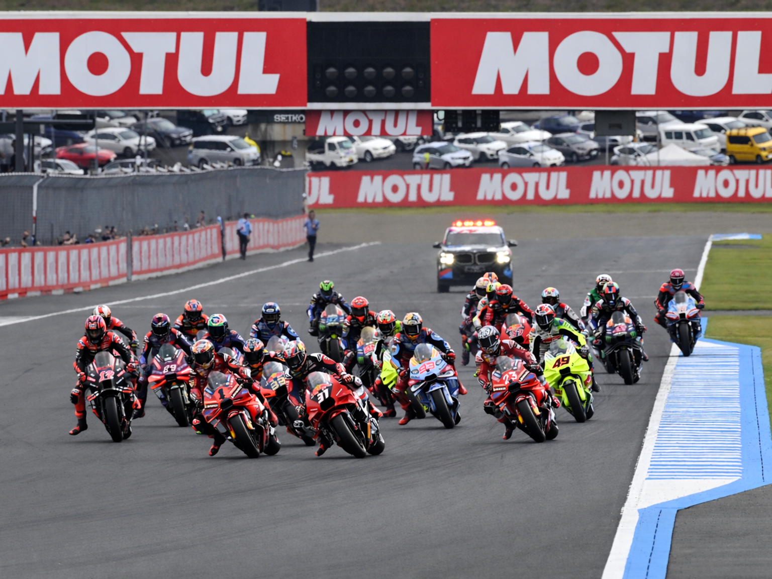 Many motorcycle racers lean into a turn on a race track.