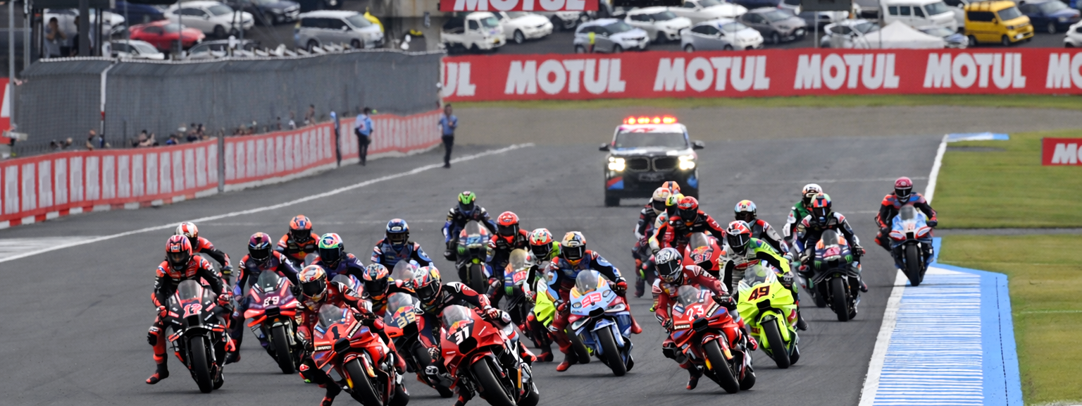 Muchos pilotos de motociclismo se inclinan en una curva en un circuito de carreras.