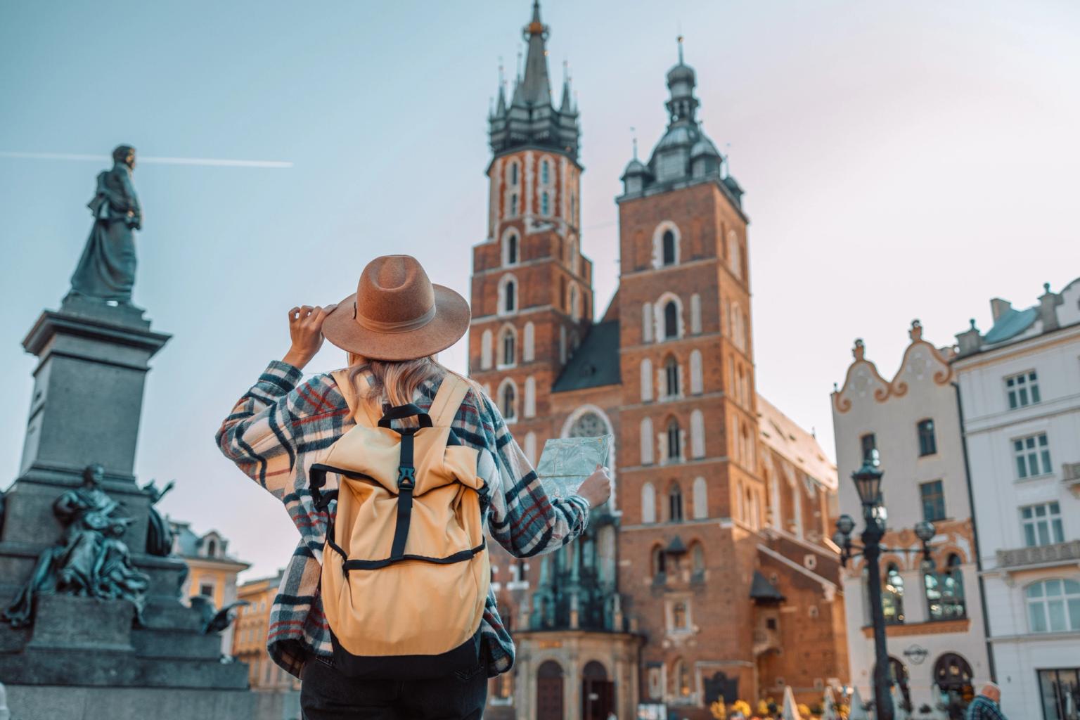 a woman with a backpack is looking at a map in front of a castle