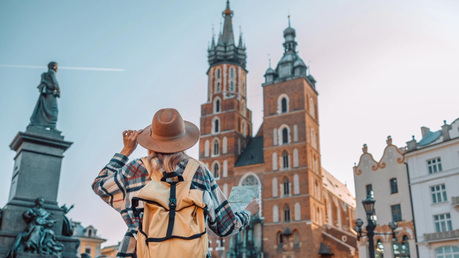 a woman with a backpack is looking at a map in front of a castle