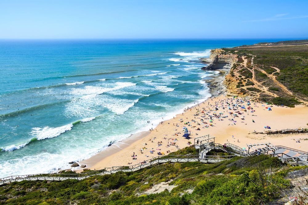 a beach with a lot of people on it and stairs leading up to it