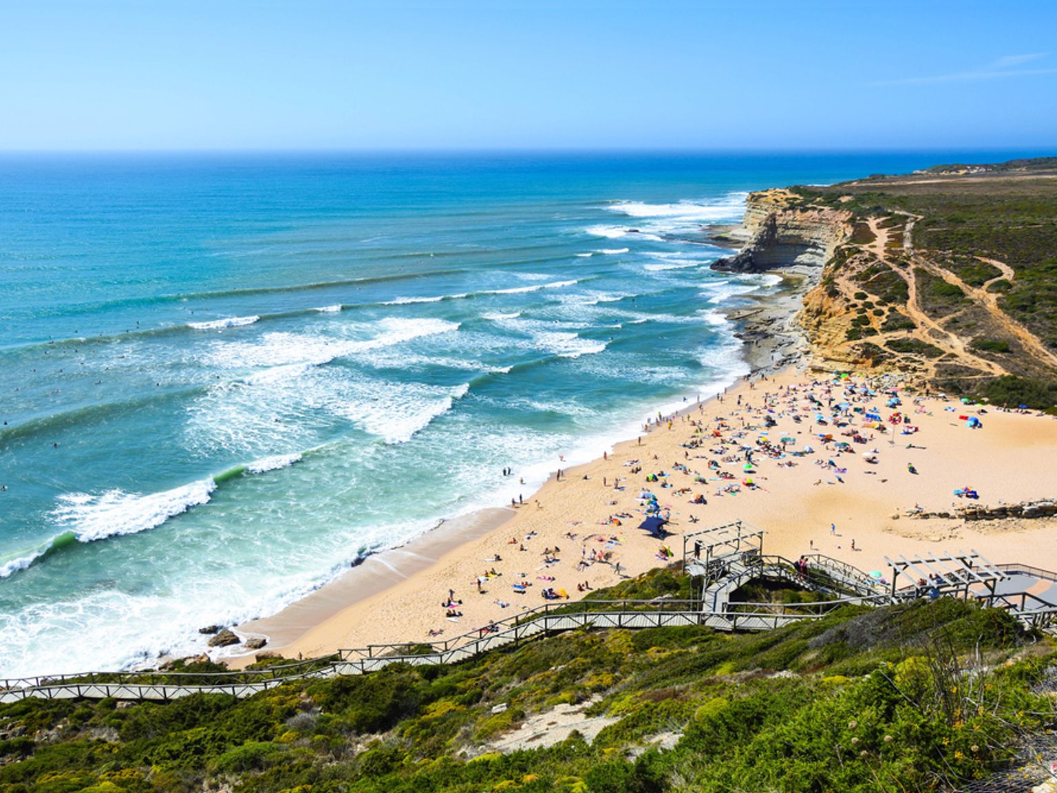 a beach with a lot of people on it and stairs leading up to it