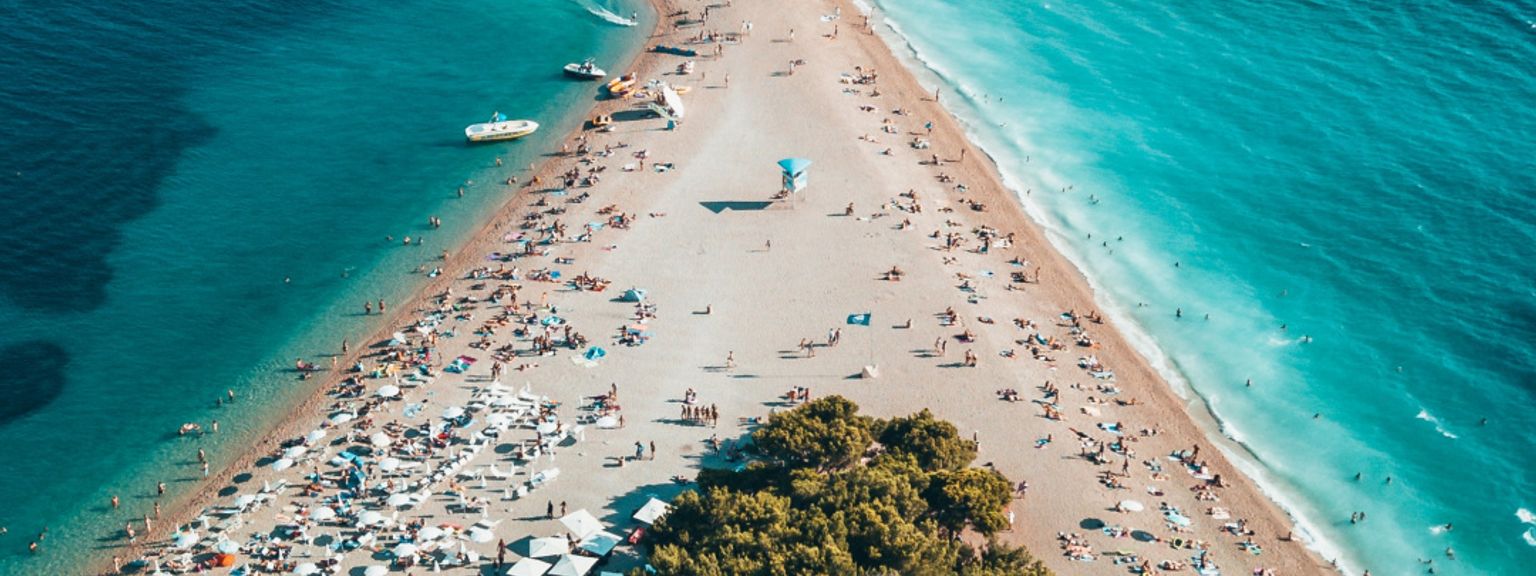 en luftig utsikt over en strand fylt med mennesker og paraplyer