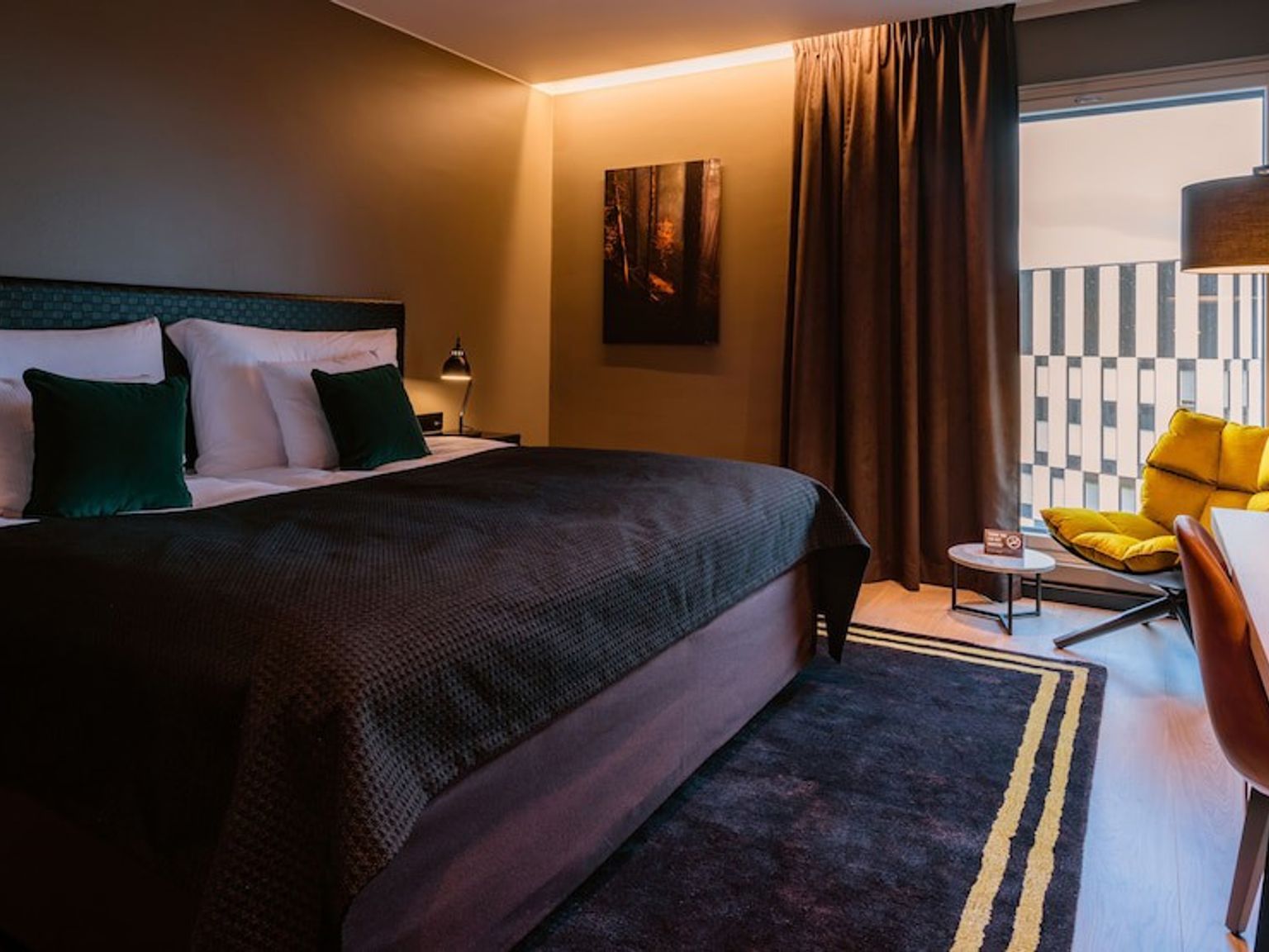 a hotel room with a large bed, chair, desk and window