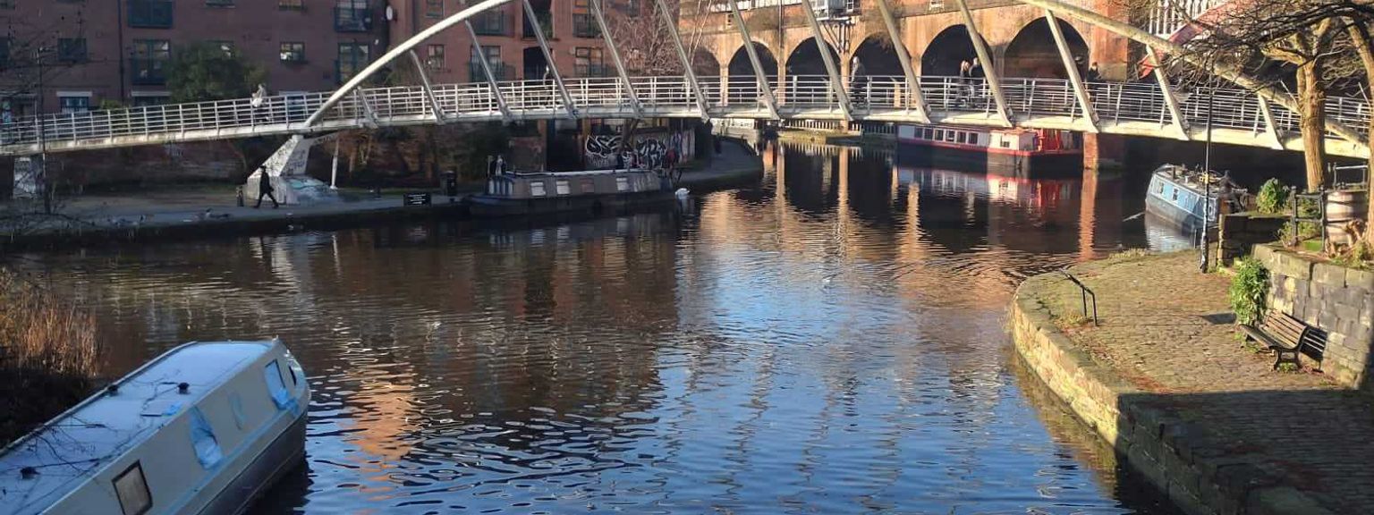 en bro over en elv med en båt i forgrunnen