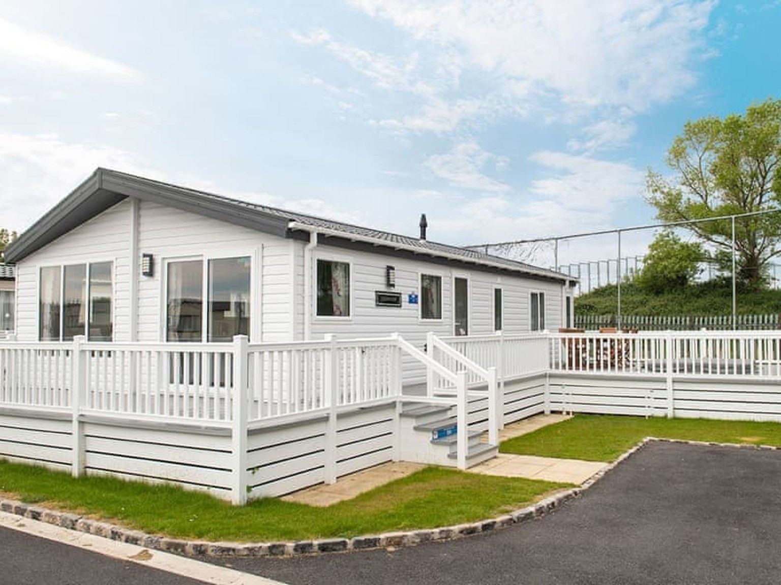 a white mobile home with a large deck and stairs