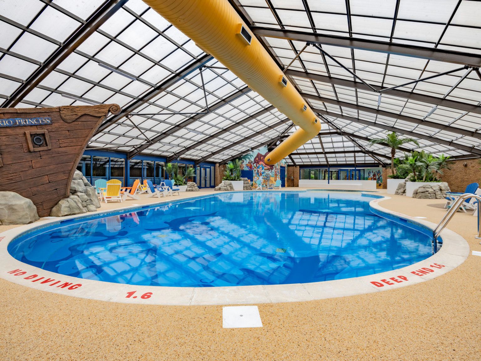 a large indoor swimming pool with a pirate ship in the background