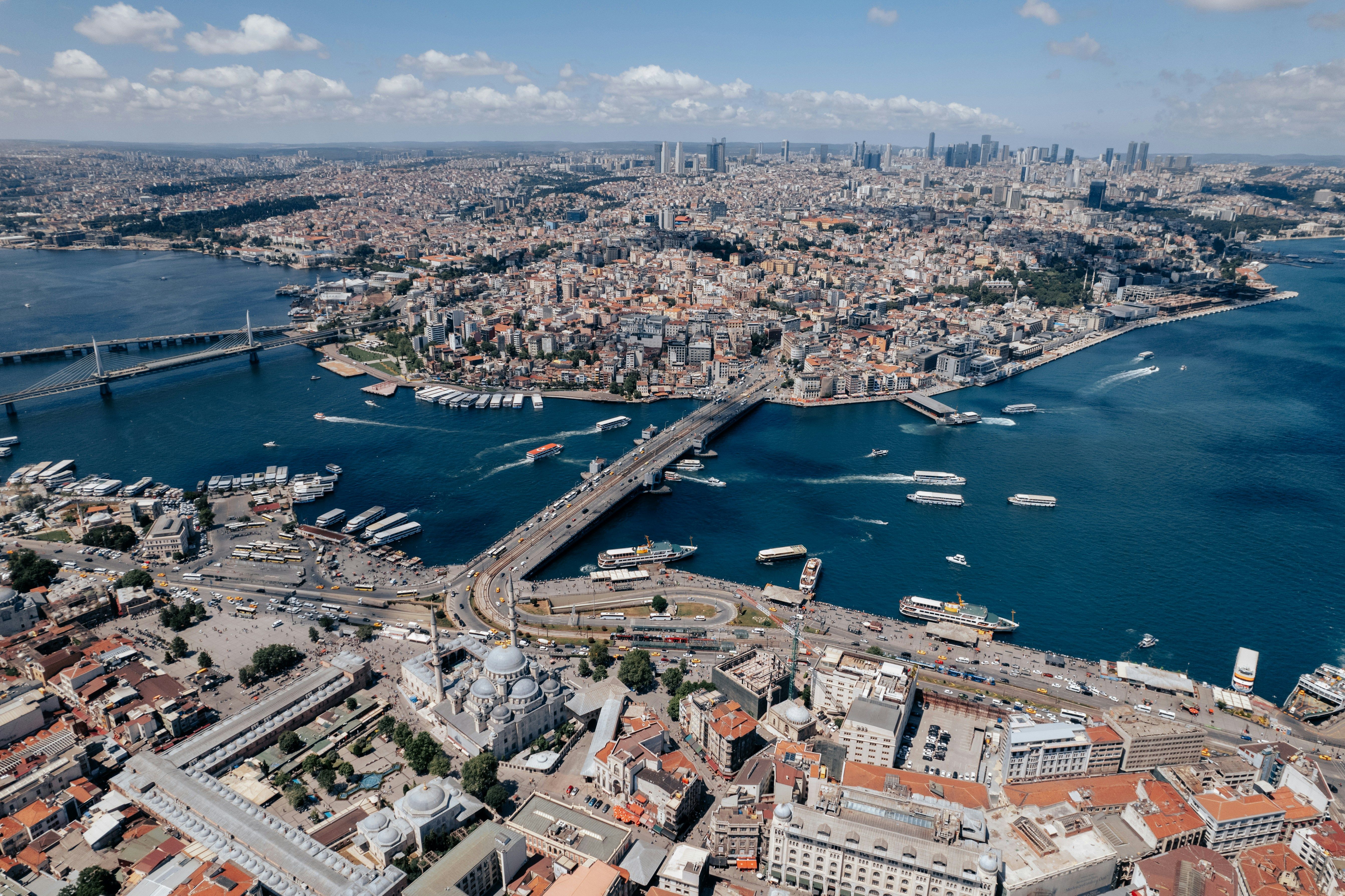 Luftfoto af Istanbuls Gyldne Horn med broer, både, en storslået moské og et tæt bylandskab.
