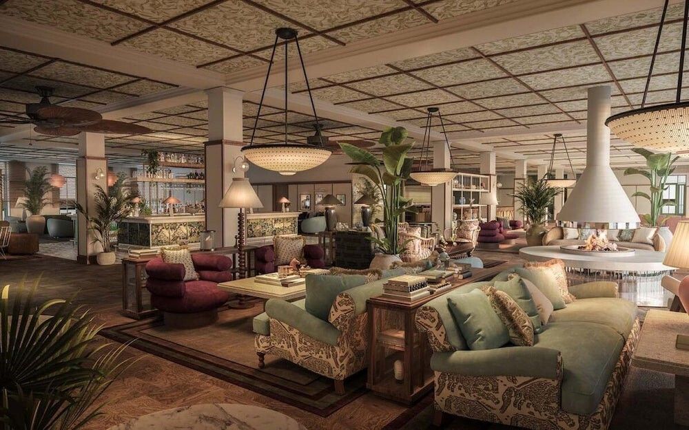 En stilren, rymlig hotellobby med olika sittgrupper, en bar, många växter och en modern konformad eldstad. Rox Resort