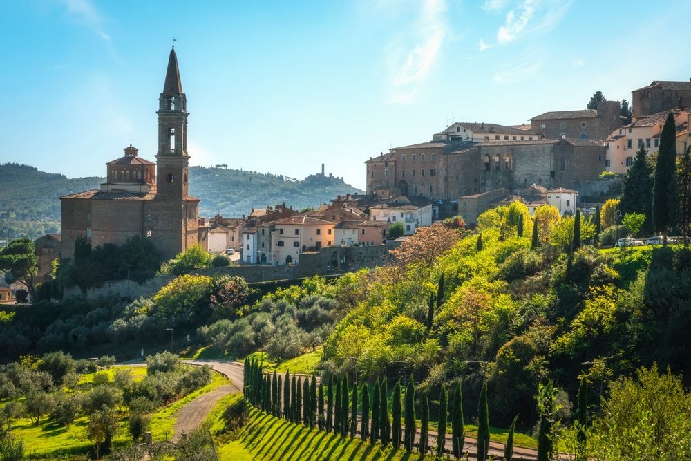 Italiensk bakkeby med en fremtredende kirke, olivenlunder og sypresser. Castiglion Fiorentino