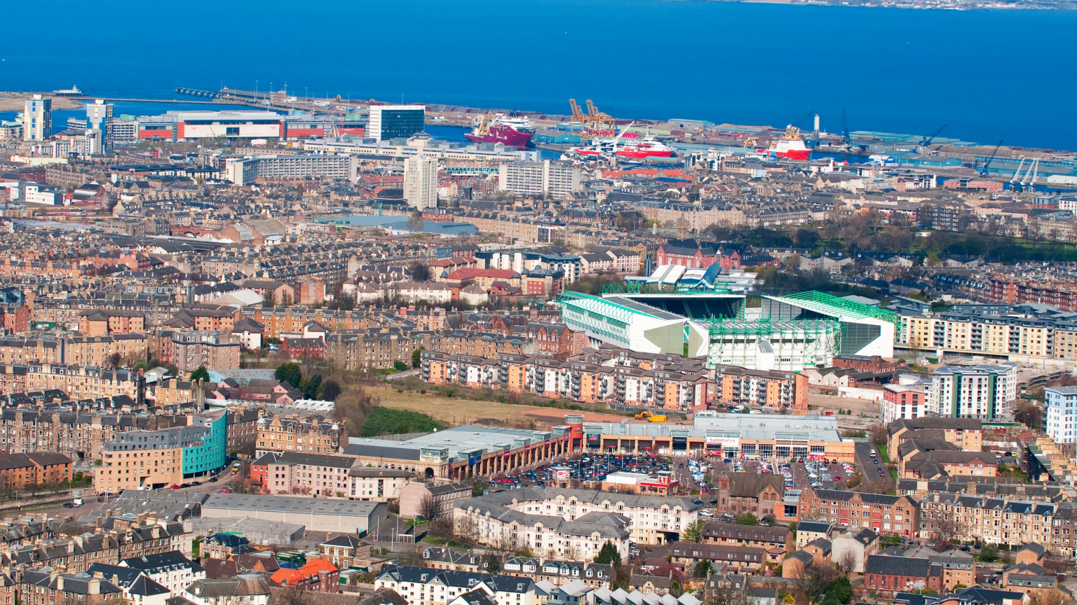Aerial view of a coastal city with a stadium and a port.