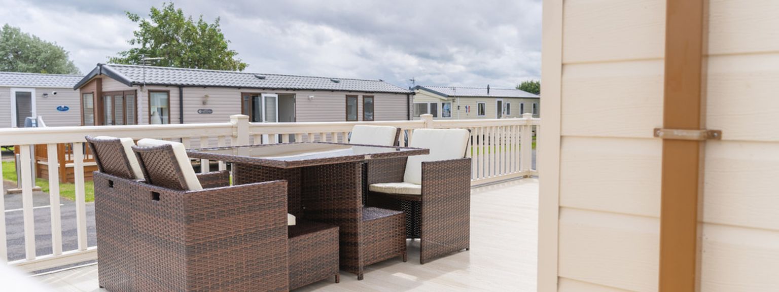 there is a table and chairs on the deck of a mobile home.
