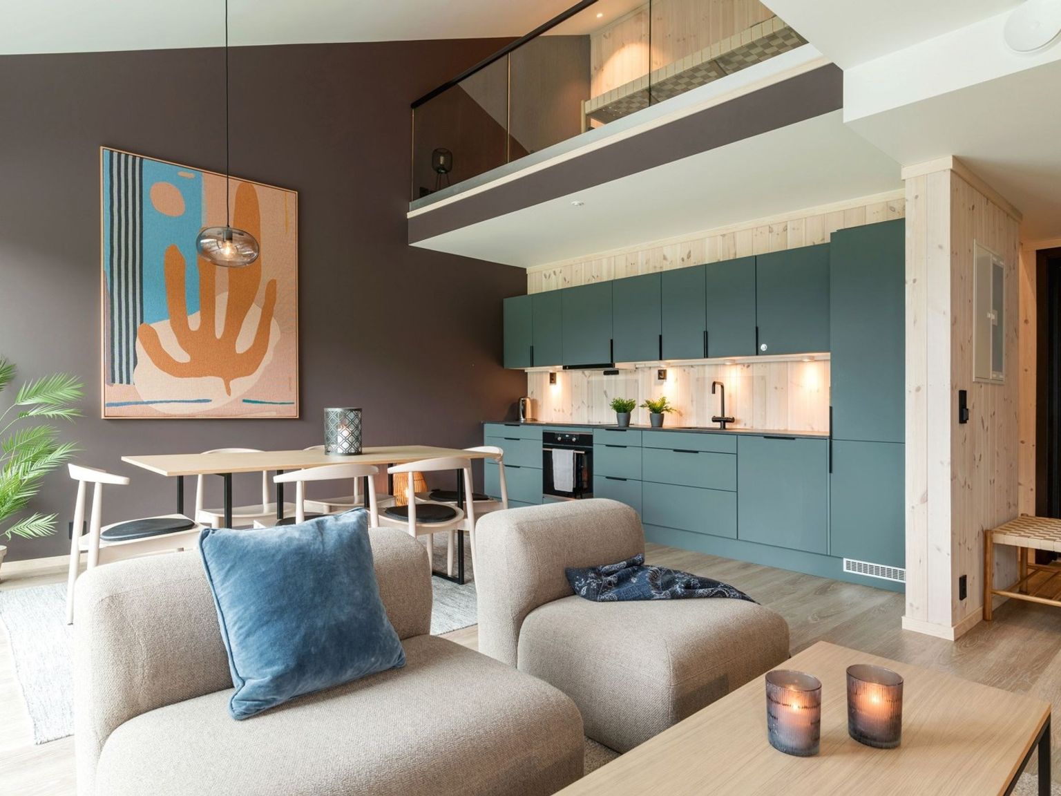 ett vardagsrum med en soffa, stol, bord och kök.