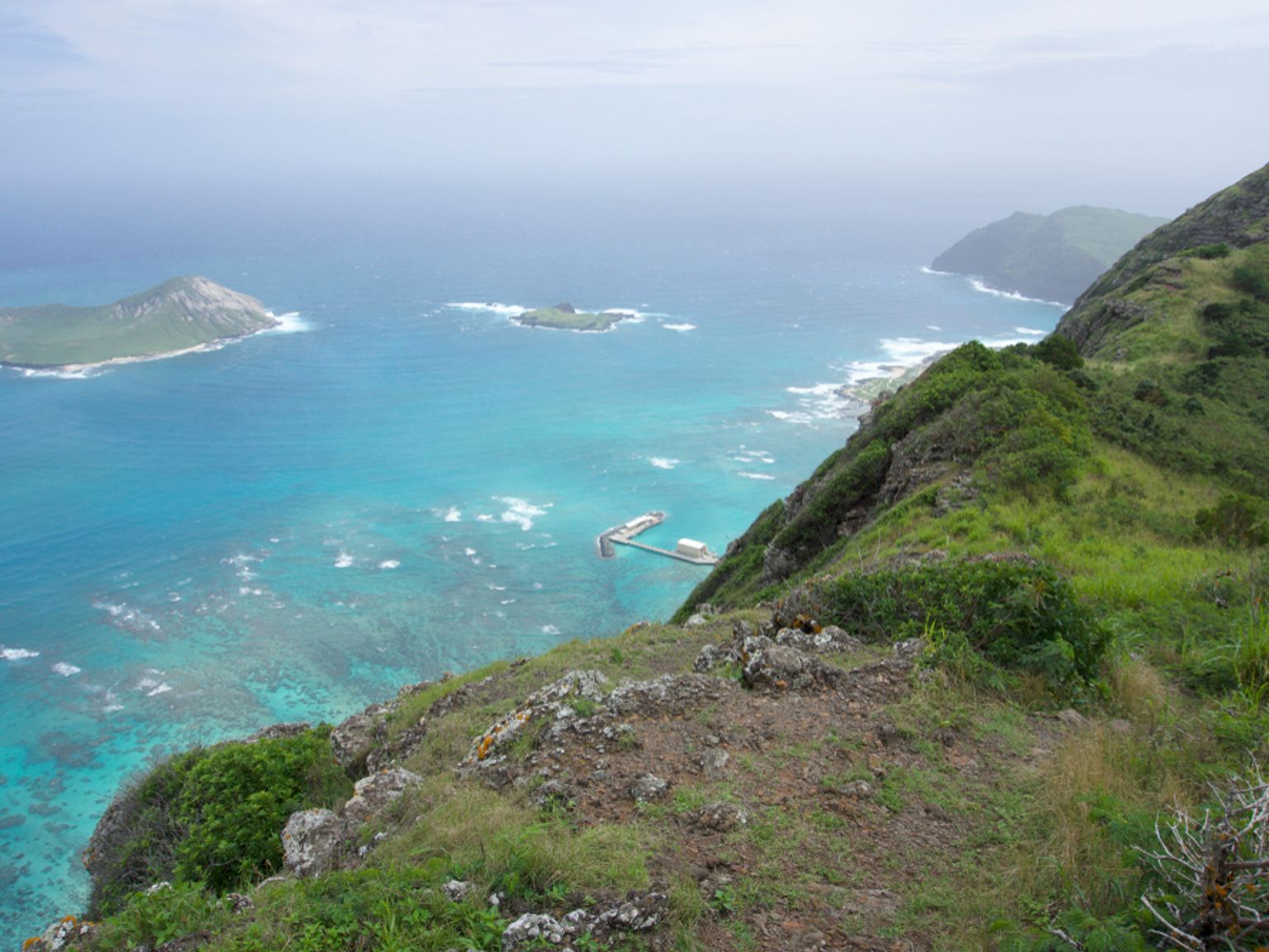a view of a small island in the middle of the ocean from a cliff