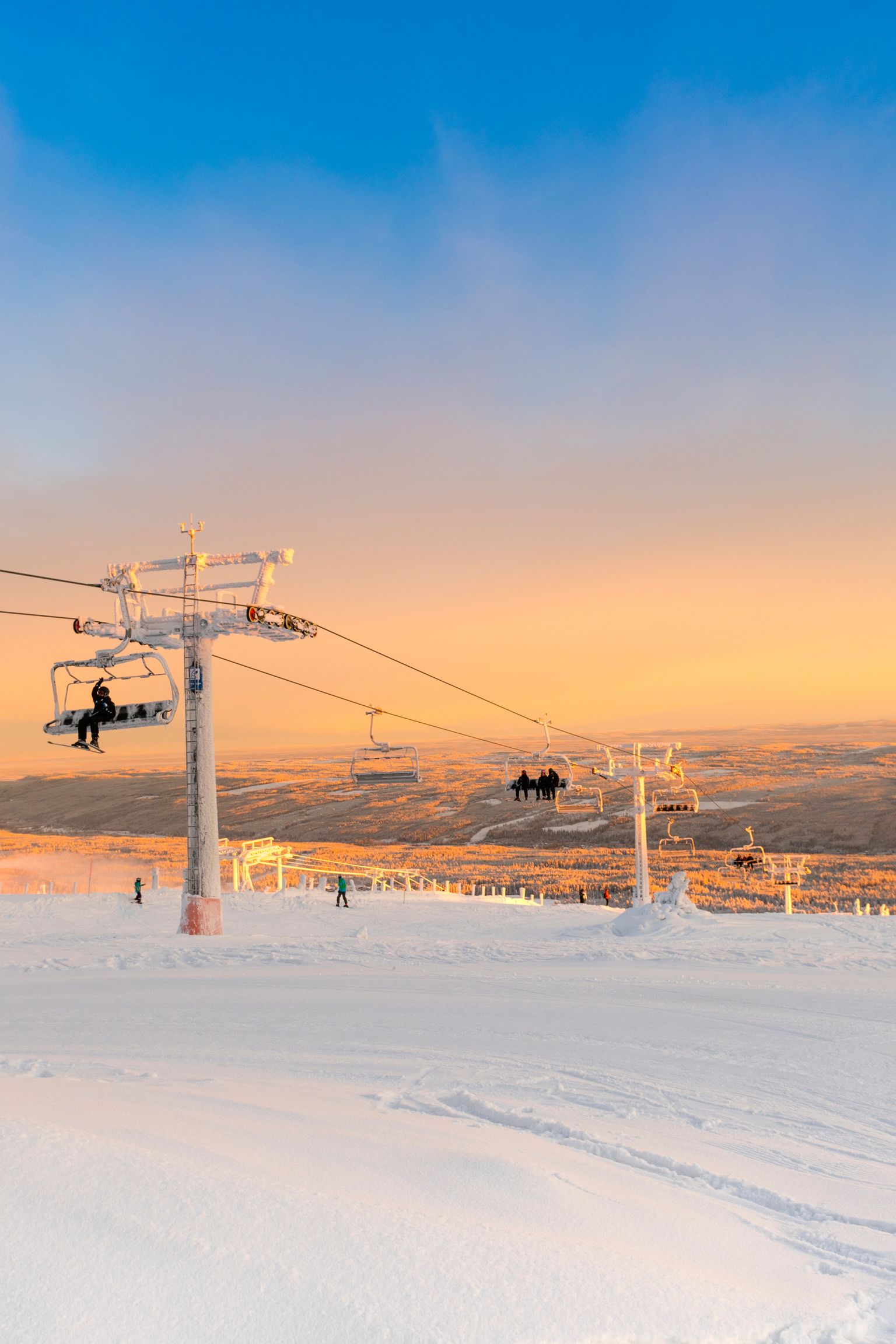 wyciąg narciarski przewożący ludzi na pokrytym śniegiem stoku o zachodzie słońca