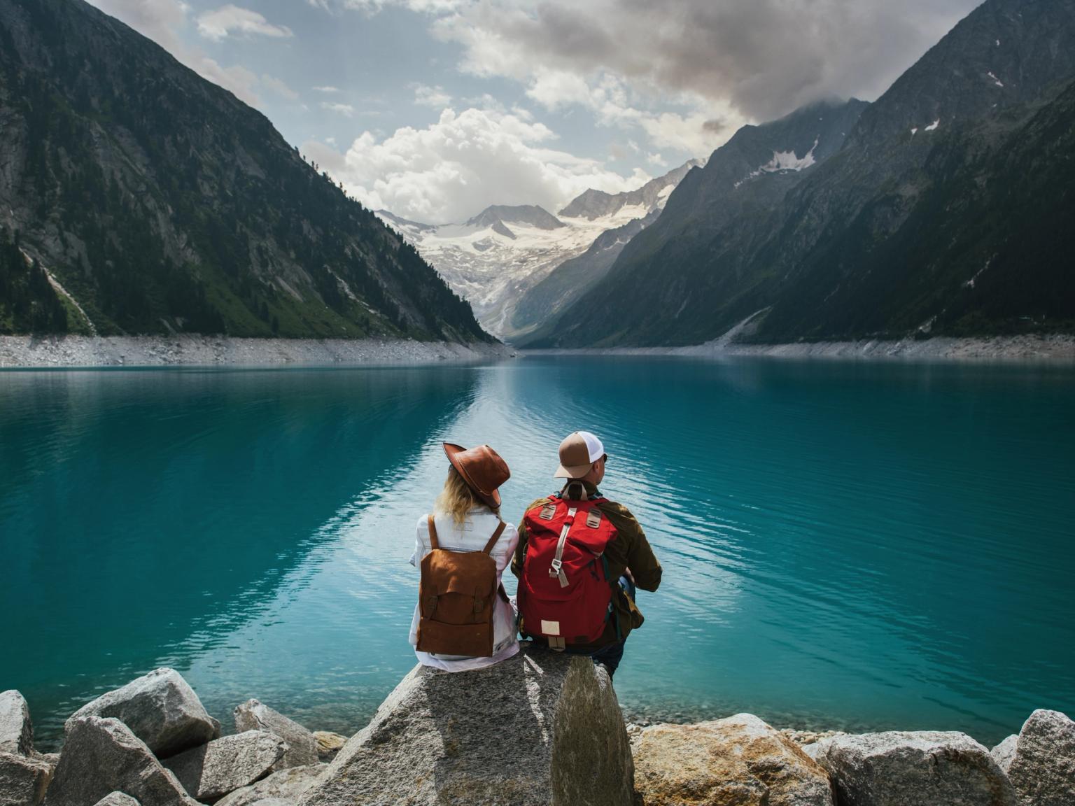 a man and a woman are sitting on a rock near a lake
