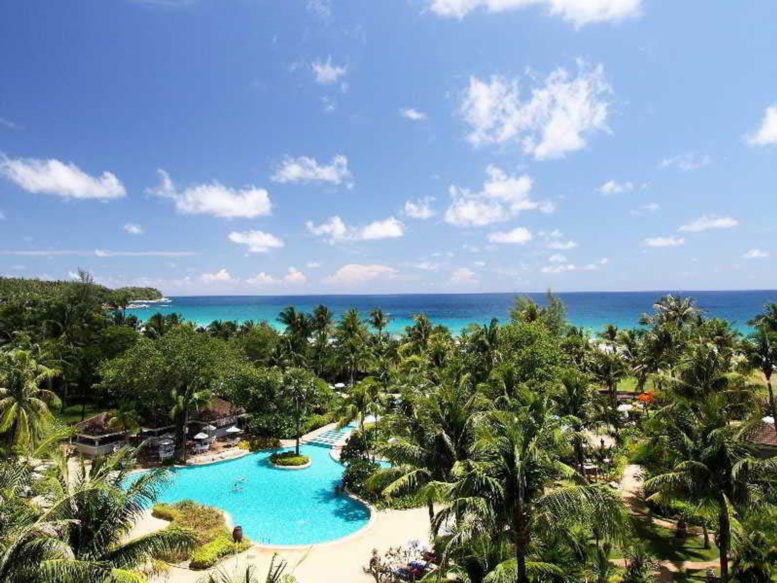 en luftig utsikt over en tropisk resort med et stort svømmebasseng omgitt av palmetrær