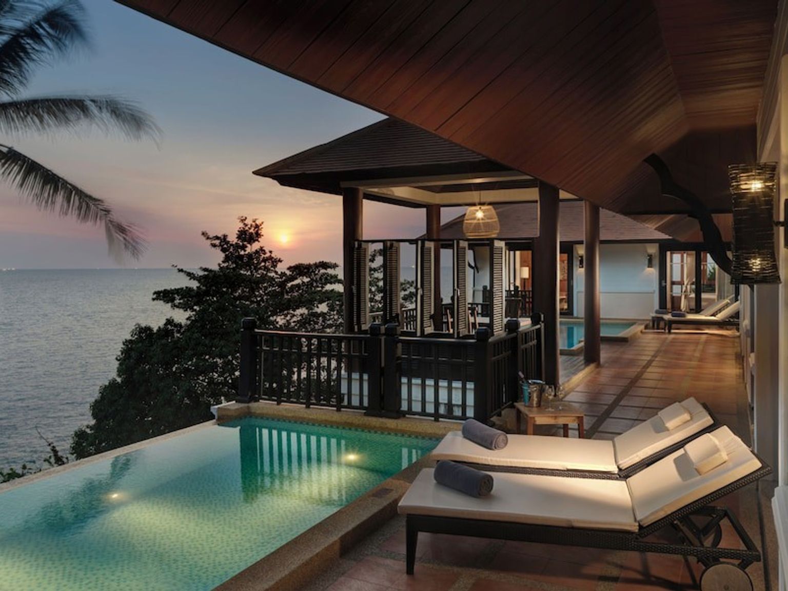 eine Villa mit einem Swimmingpool mit Blick auf den Ozean bei Sonnenuntergang