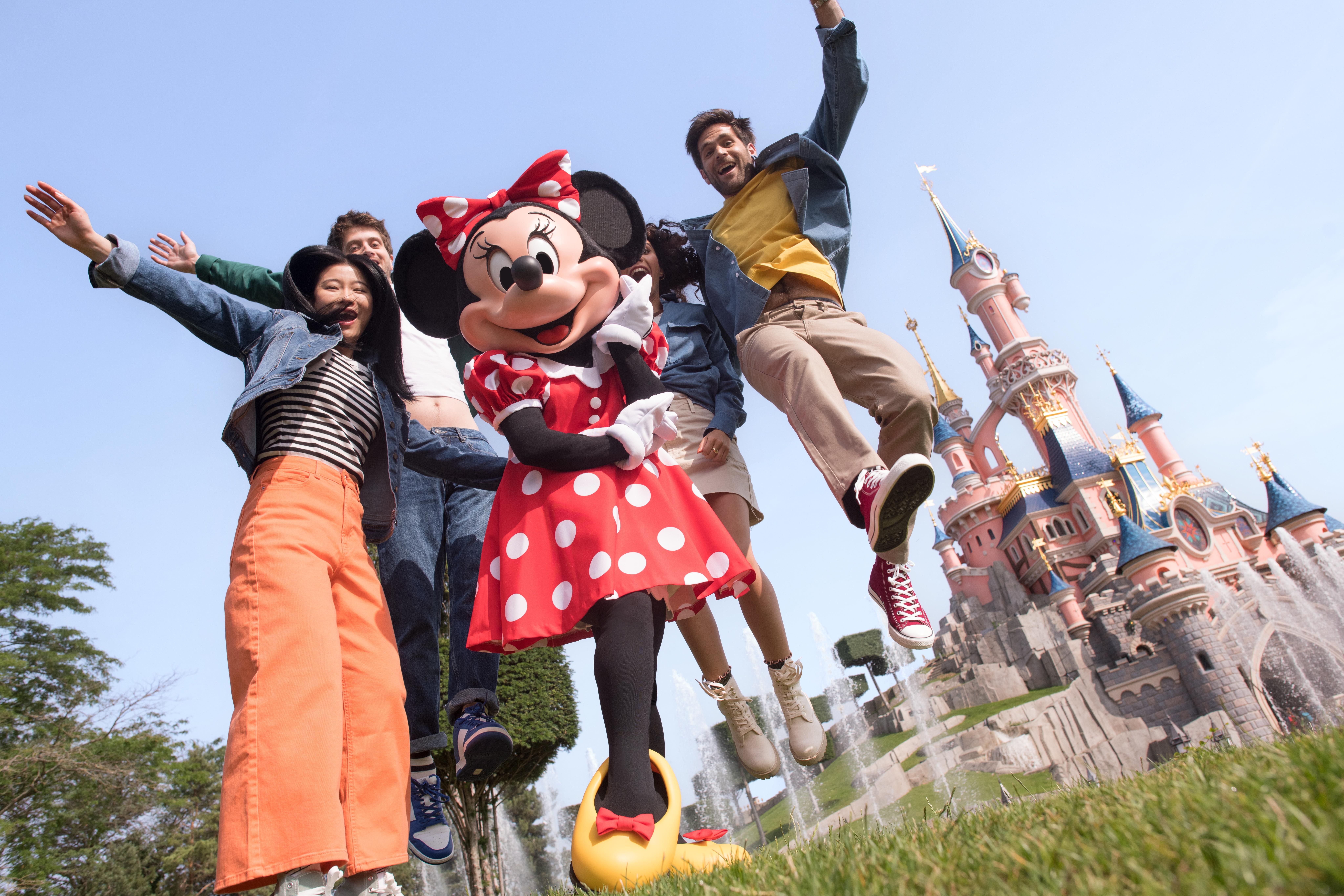 en grupp människor poserar för en bild med minnie mouse framför ett slott