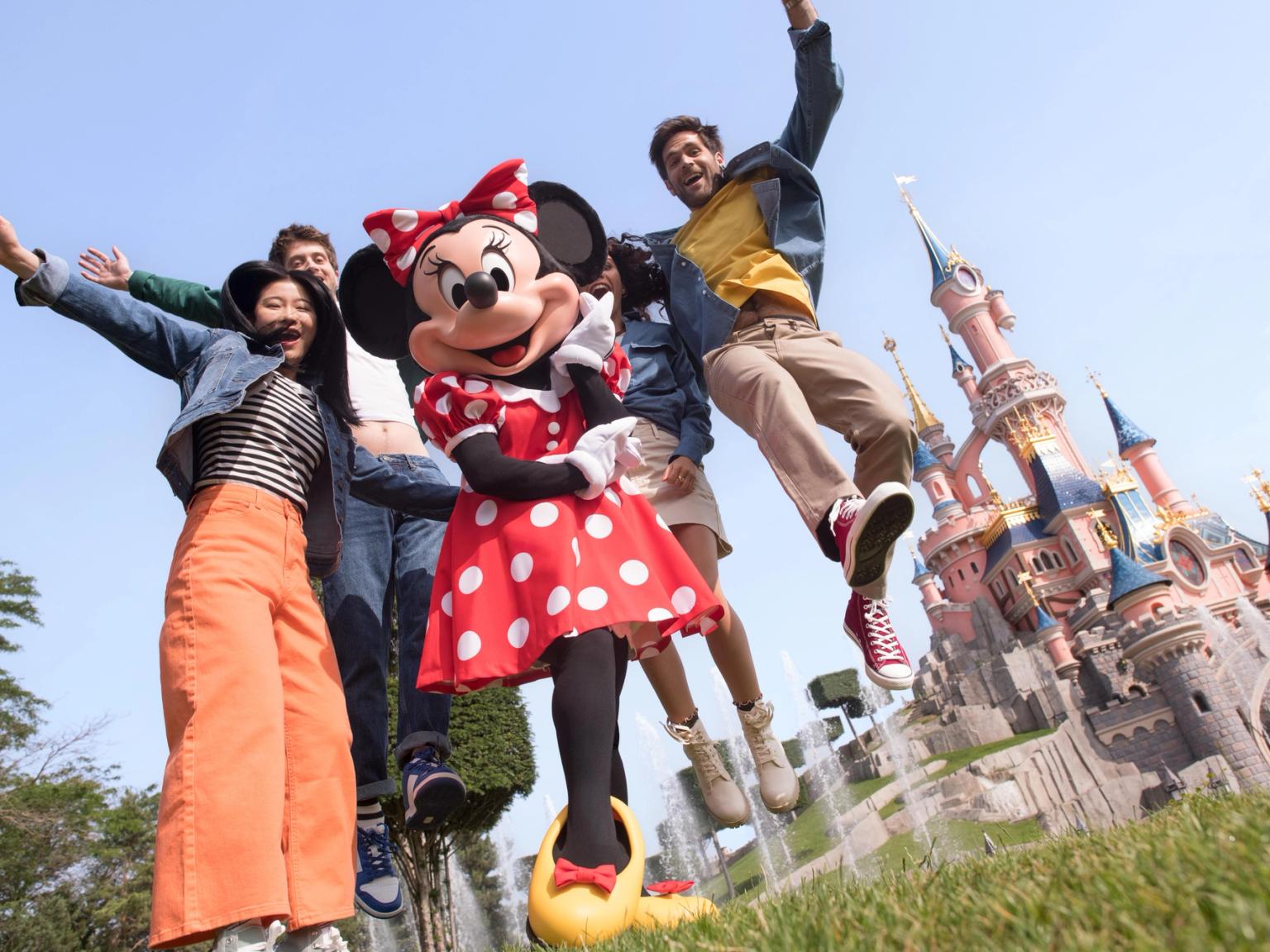 en gruppe mennesker poserer for et billede med minnie mouse foran et slot