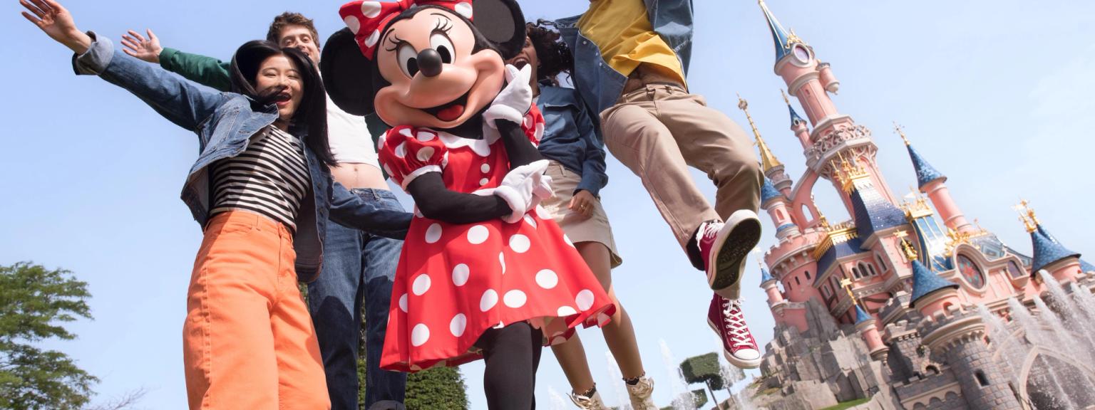 en gruppe mennesker poserer for et billede med minnie mouse foran et slot
