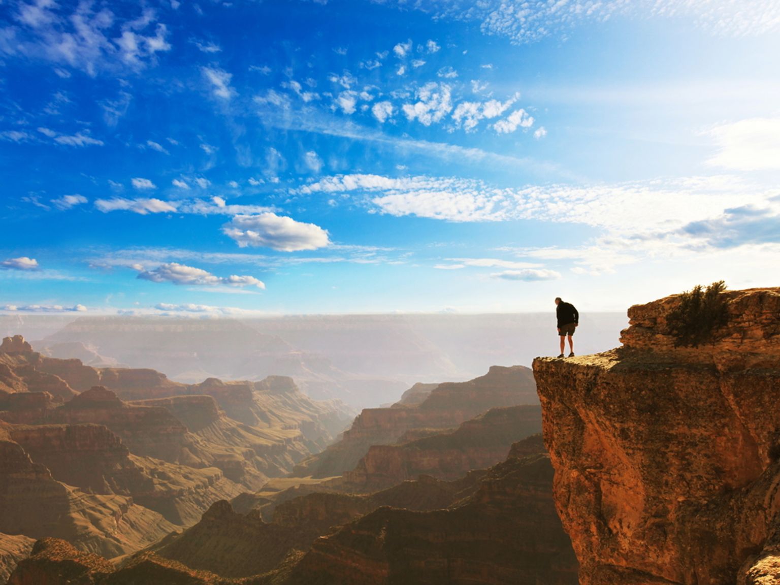 En person står på en klippekant og ser utover Grand Canyon.