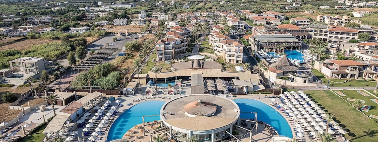 en flygvy över en stor swimmingpool omgiven av palmer och parasoller