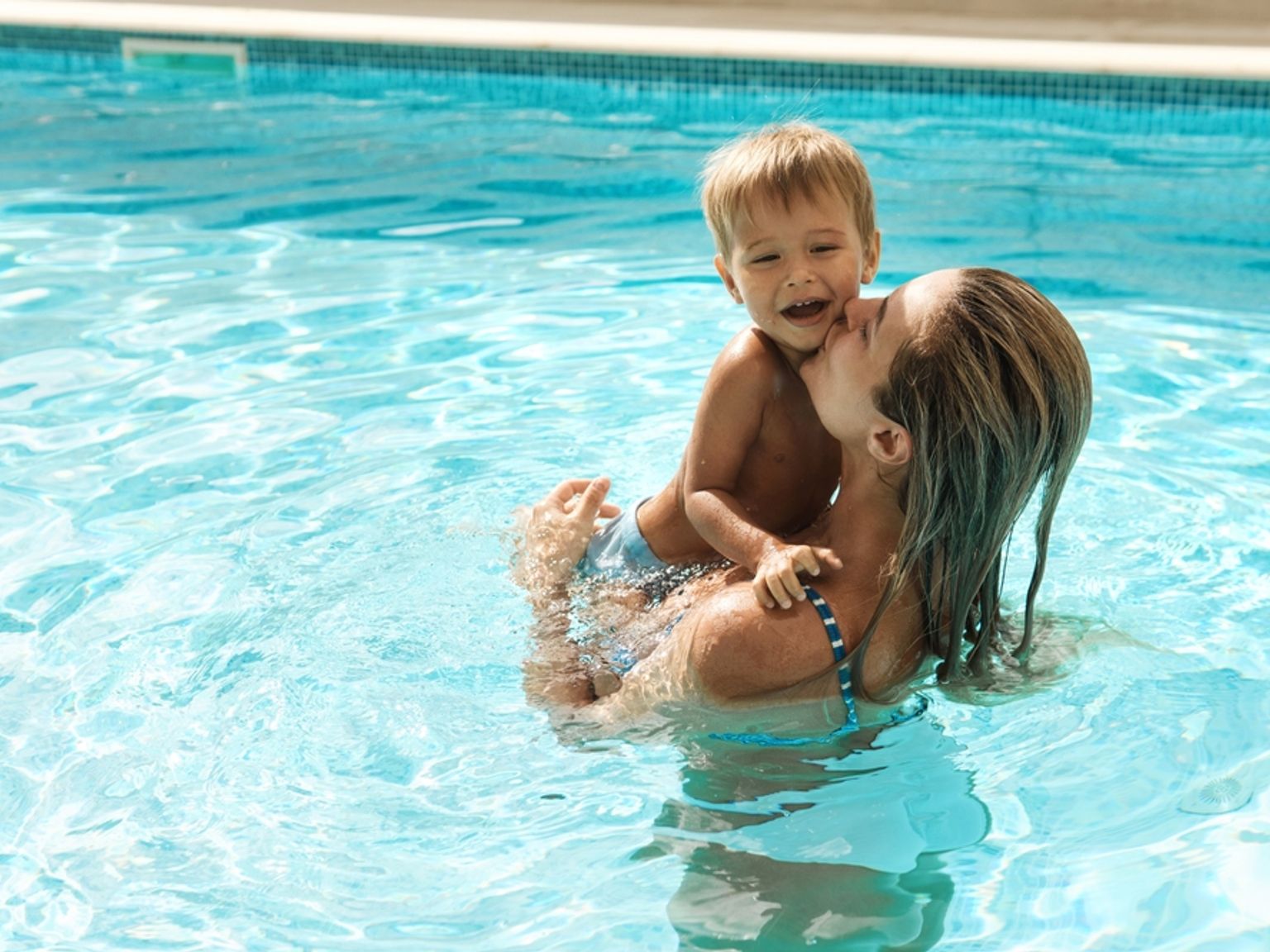 en kvinna håller ett barn i en swimmingpool