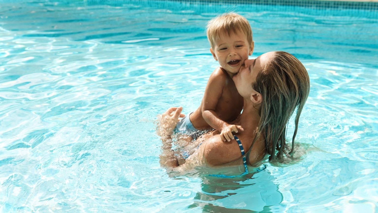 en kvinna håller ett barn i en swimmingpool