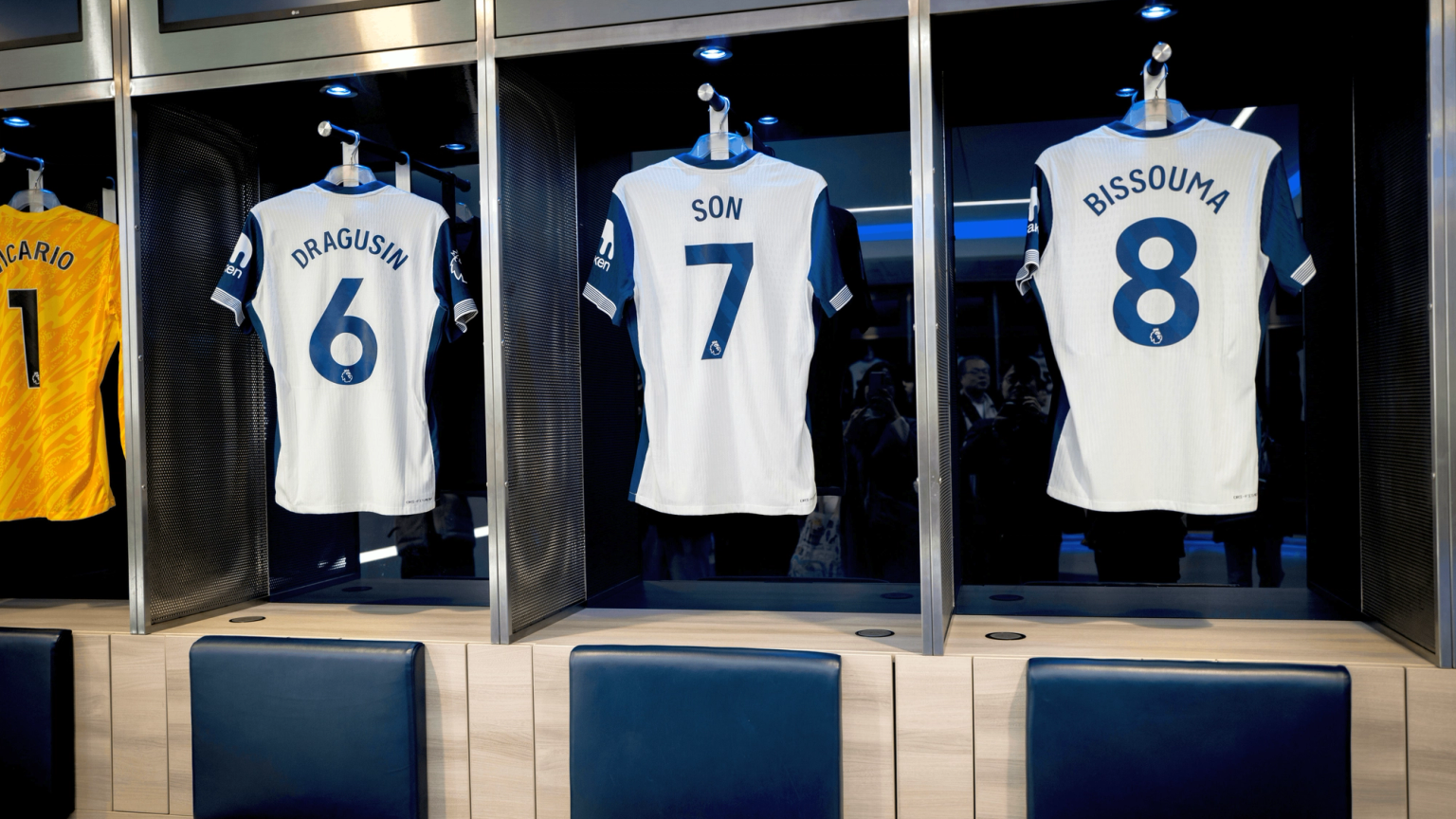 Four soccer jerseys for players Vicario (1), Dragusin (6), Son (7), and Bissouma (8) hanging in a locker room.