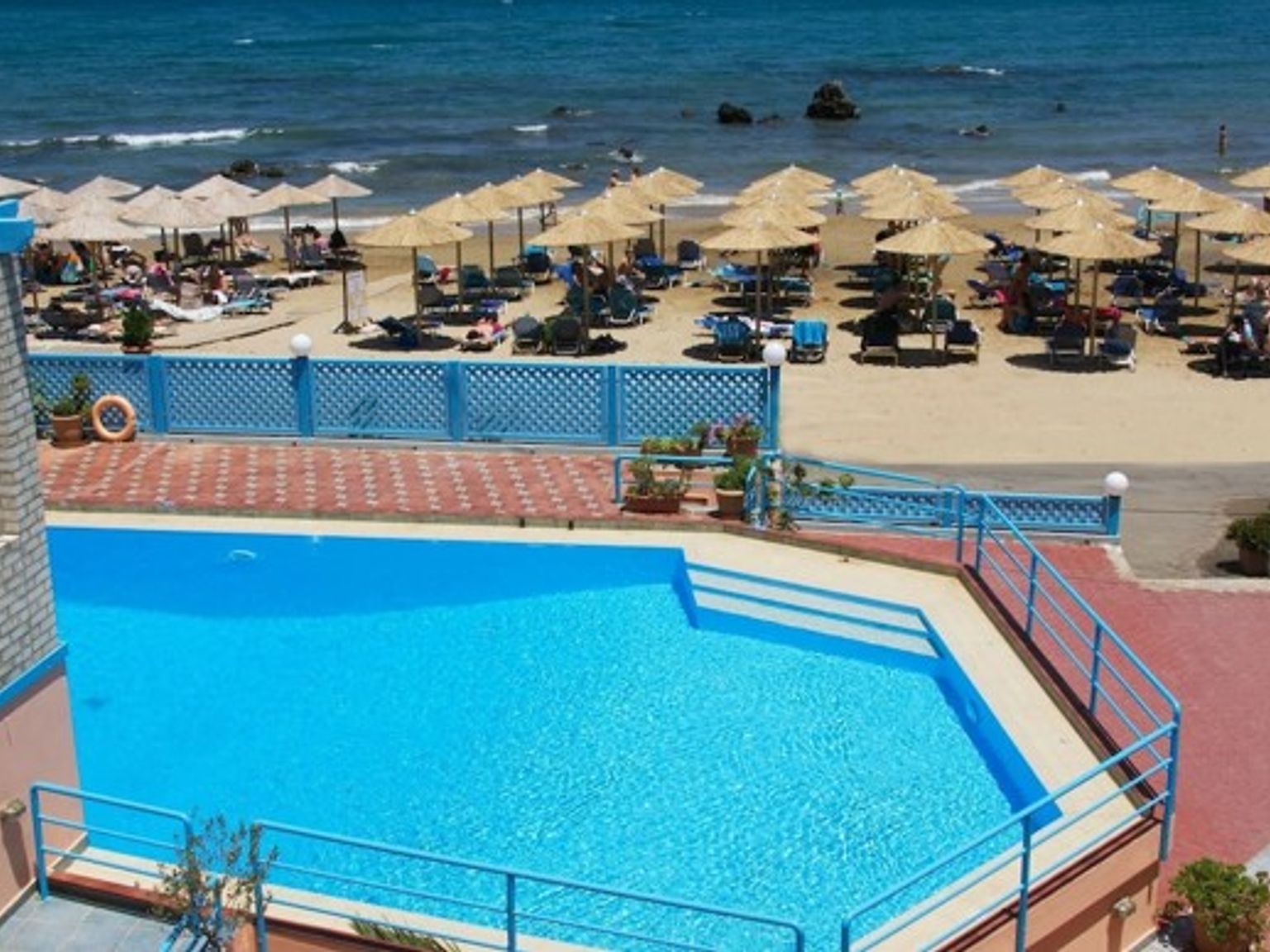 en stor simbassäng omgiven av paraplyer och stolar bredvid en strand
