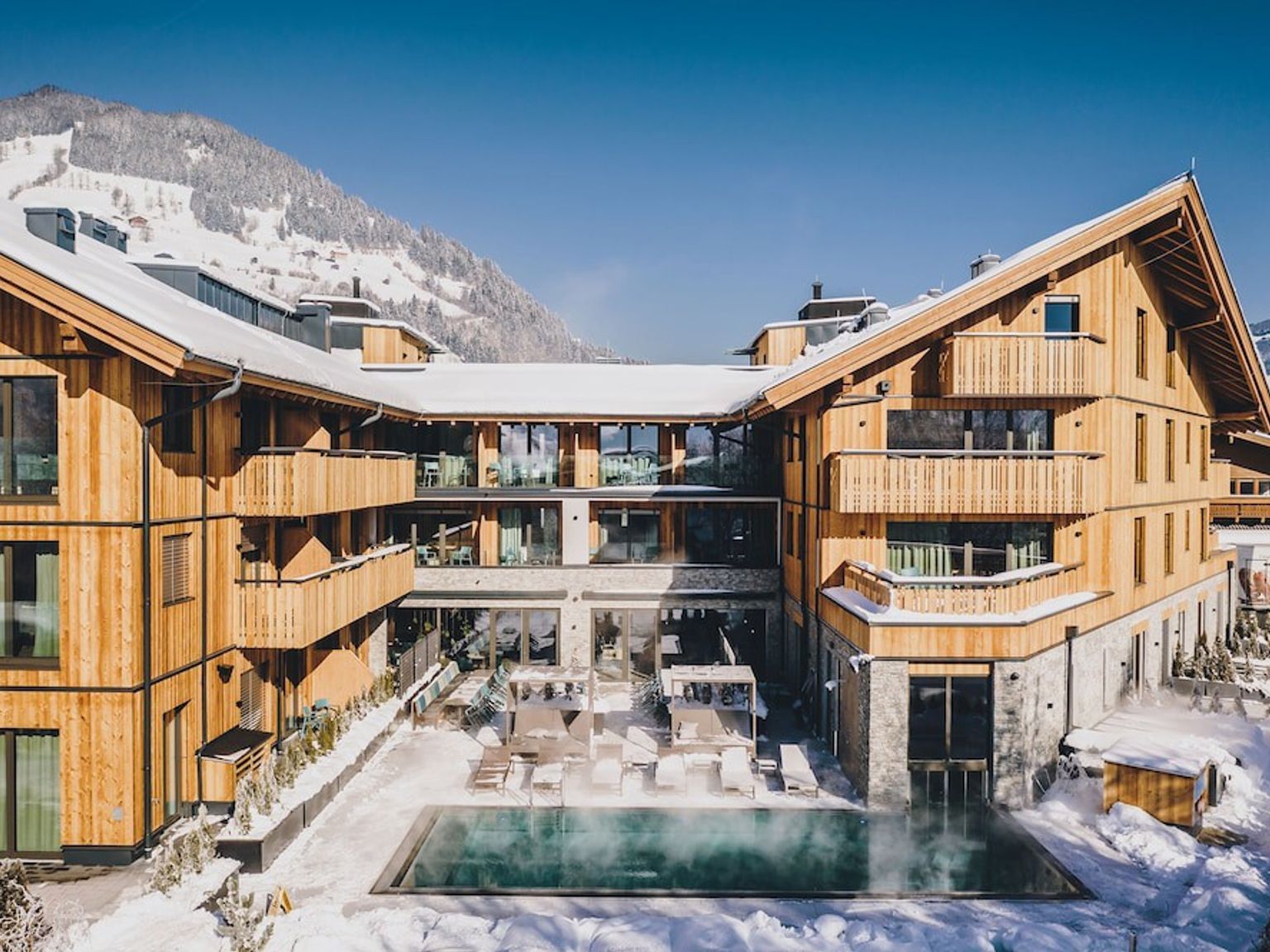 en stor trebygning med et svømmebasseng i midten av den i snøen, Elements Resort Zell am See, BW Signature Collection